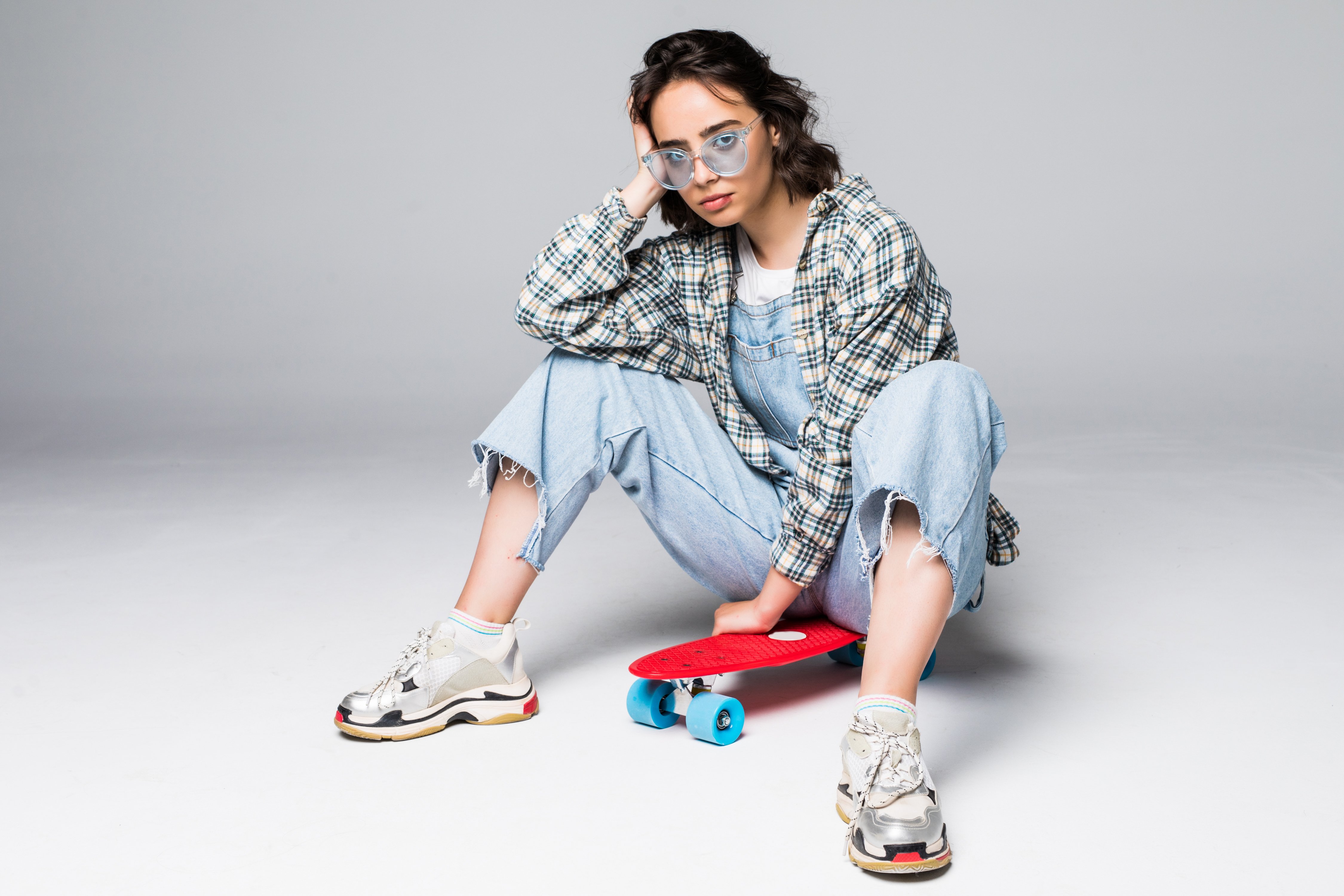 happy-attractive-young-woman-sunglasses-sitting-skateboard